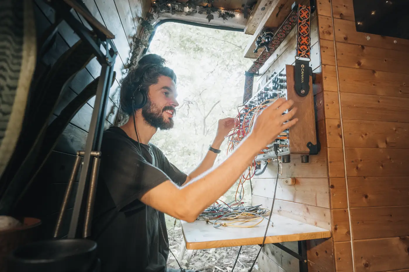 Mike Hudson inside his van-home sat at the desk at the back of the van playing music