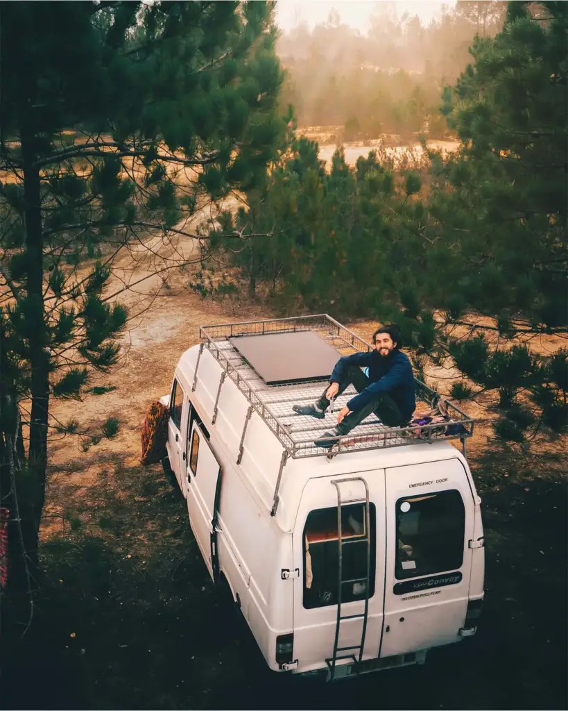 Mike sitting in the open side door of the van with a mug of coffee, feet up on the step, a landscape stretching out behind him.